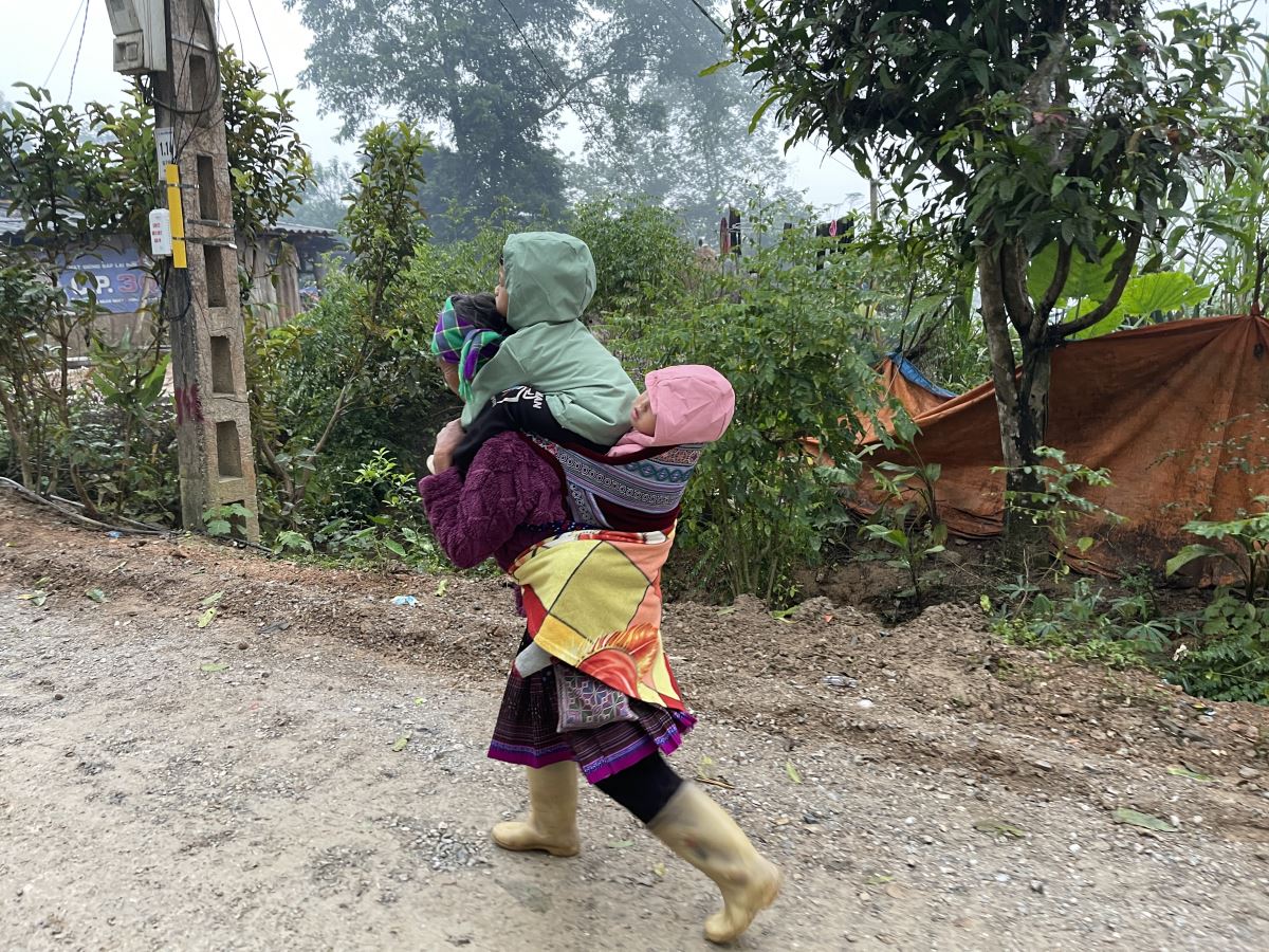 Bà địu hai cháu trên lưng giữa mùa đông vùng cao — hình ảnh giản dị mà lặng lòng